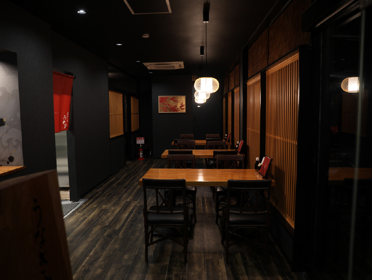 モダンな和の照明が灯る、半個室のテーブル席へと続く落ち着いた通路